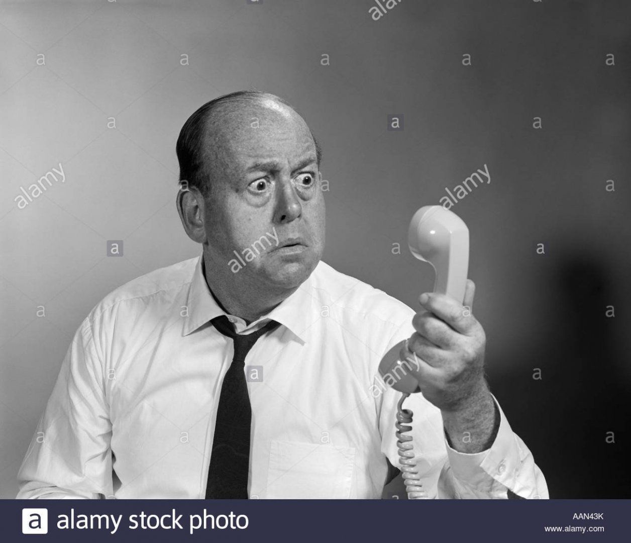 1960s-balding-man-looking-angry-into-telephone-receiver-AAN43K.jpg